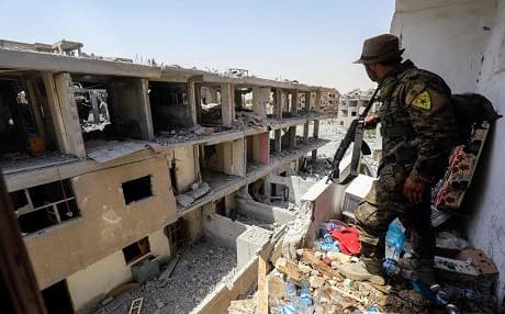 A member of the Kurdish People's Protection Units (YPG), the armed wing of the Kurdish Democratic Party (PYD), moves through destroyed buildings in Raqqa on Friday. Photo: Delil Souleiman | AFP
