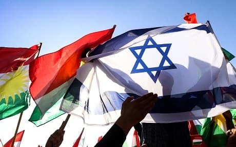 A man holds the Israeli flag as others raise the flag of the Kurdistan Region during a demonstration outside the UN Office in Erbil, the capital of the autonomous region, protesting against the escalating crisis with Baghdad. Photo: AFP/ Safin Hamed