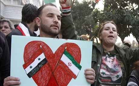 A protester holds a poster showing the Iranian and Syrian flags during a demonstration in front of the Iranian embassy in Damascus. Photo: AP