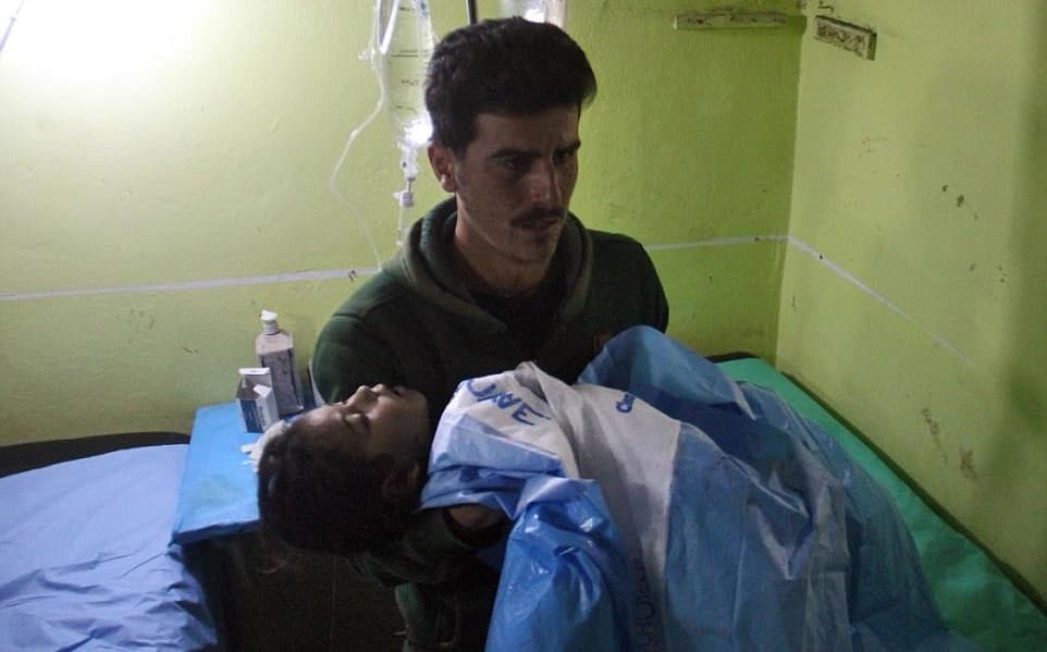A man carries an unconscious child into hospital in Khan Sheikhoun after a sarin gas attack in April. Photo: AFP