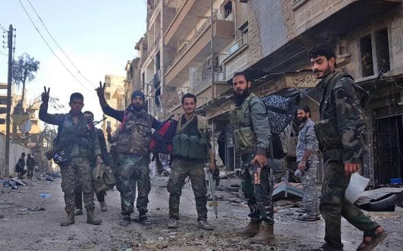 Syrian regime soldiers and allied fighters flash victory signs in war-scarred Deir ez-Zor on November 3. Photo: AFP