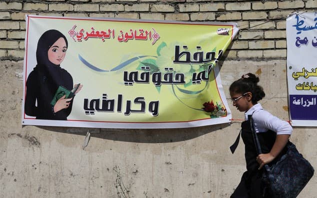 A schoolgirl passes a banner promoting the Jaafari Personal Status law in 2014. The banner states that the law "saves my rights and my dignity." File photo: Karim Kadim/AP