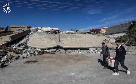 Two boys walk past a building in Darbandikhan that was levelled in Sunday’s earthquake. Photo: Sartip Othman/Rudaw