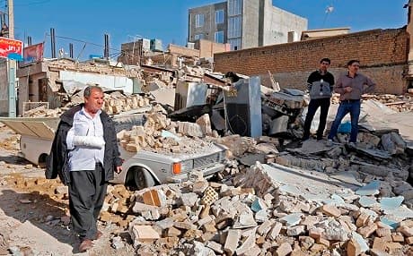 An injured man walks through rubble in the earthquake-damaged Kurdish town of Sarpol-e Zahab. Photo: Atta Kenare | AFP
