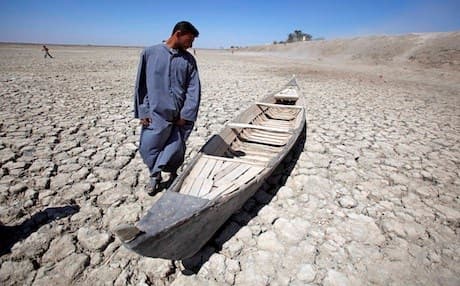 An Iraqi man stands next to his boat in a dried marsh in Hor al-Hammar area in southern Iraq. AP file photo