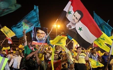 Demonstrators hoist Syrian regime, Iranian and Hezbollah flags. Photo: AP