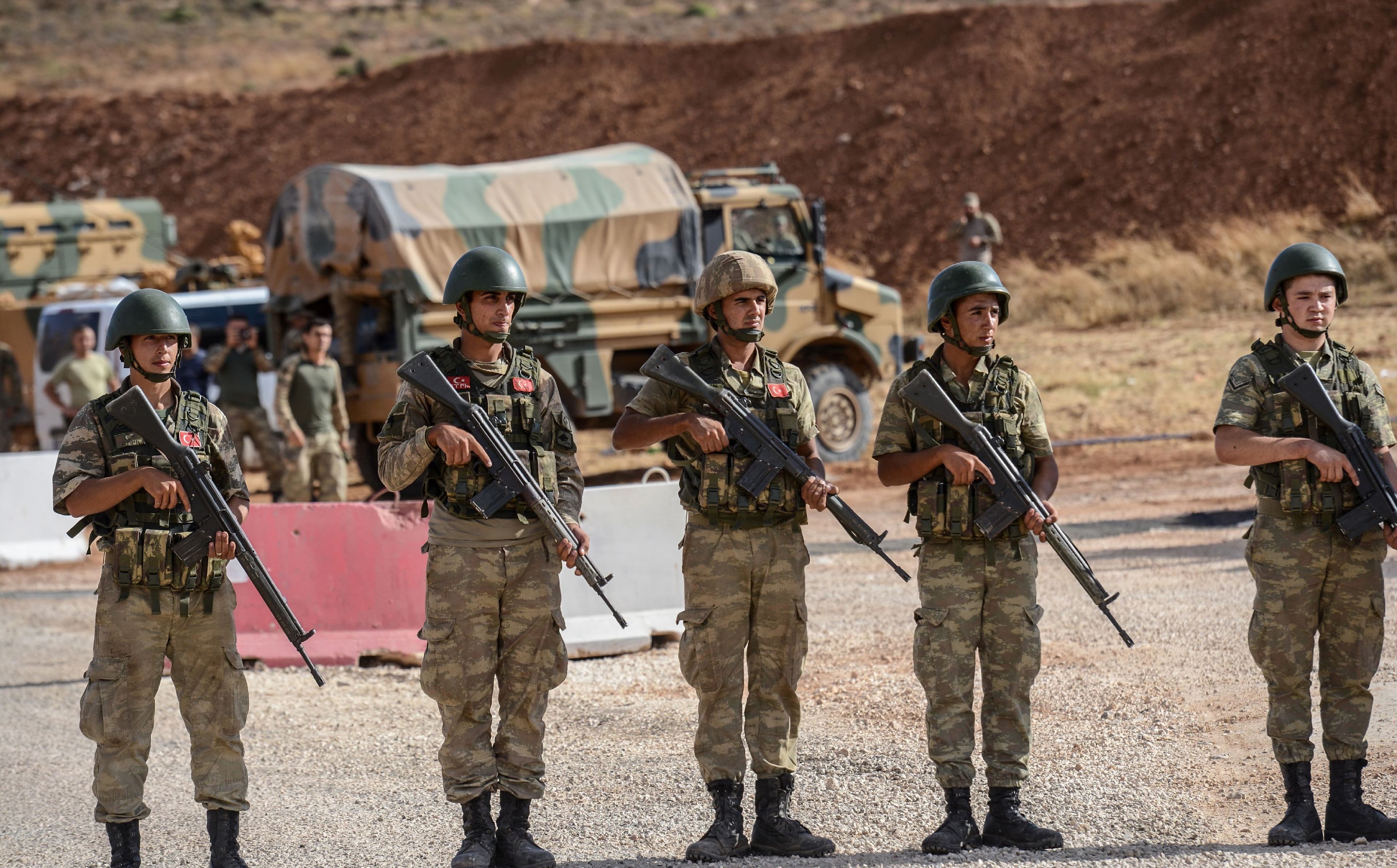 Turkish soldiers stand near armoured vehicles near the Turkey-Syria border. Photo: Ilyas Akengin/AFP