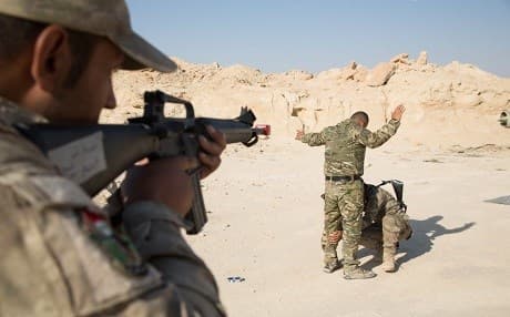 An Iraqi soldier guards a prisoner while a fellow soldier searches him during border guard training at Camp Al Asad, Iraq on August 14. Photo: Spc. Cole Erickson | US Army