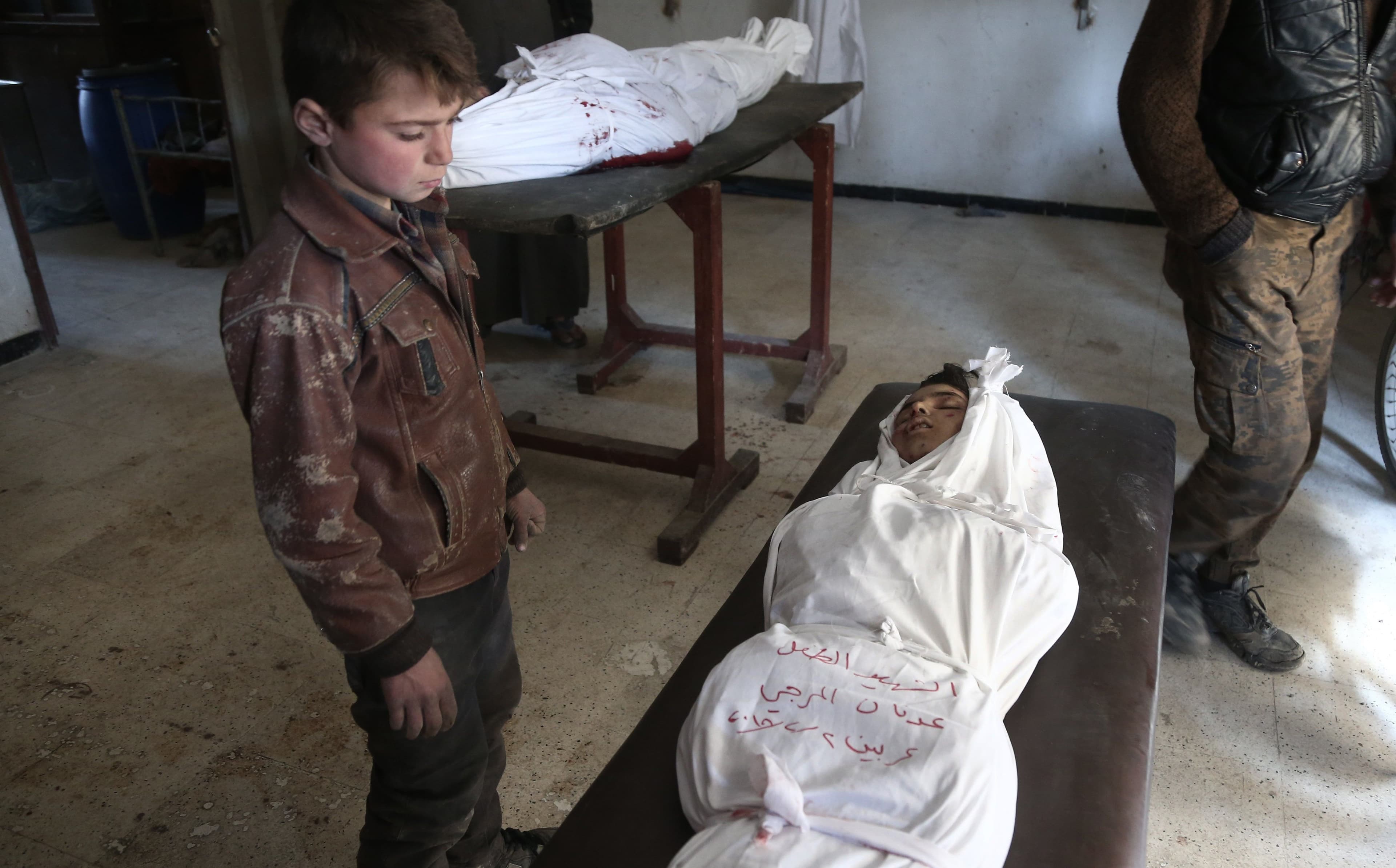 A Syrian child stands over the body of a child in a makeshift hospital following an airstrike on the rebel-held town of Arbin, in eastern Ghouta on Friday. Photo: Abdulmonam Eassa/AFP