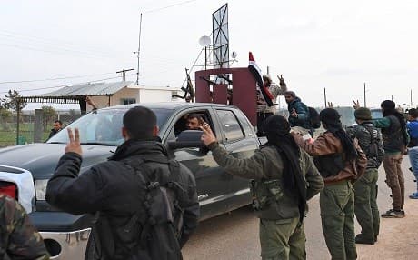 A picture taken on February 20, 2018 shows Kurdish fighters flashing the victory gesture as they welcome a convoy of pro-Syrian government fighters in Afrin, a district in Aleppo governorate. Photo: George Ourfalian | AFP