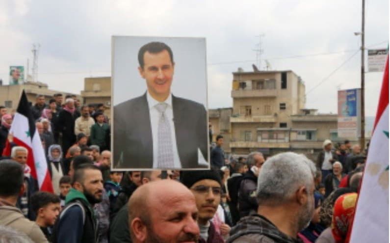 People wave Syrian flags and a portrait of President Bashar al-Assad in Afrin on Thursday. Photo: Ahmad Shafie Bilal/AFP