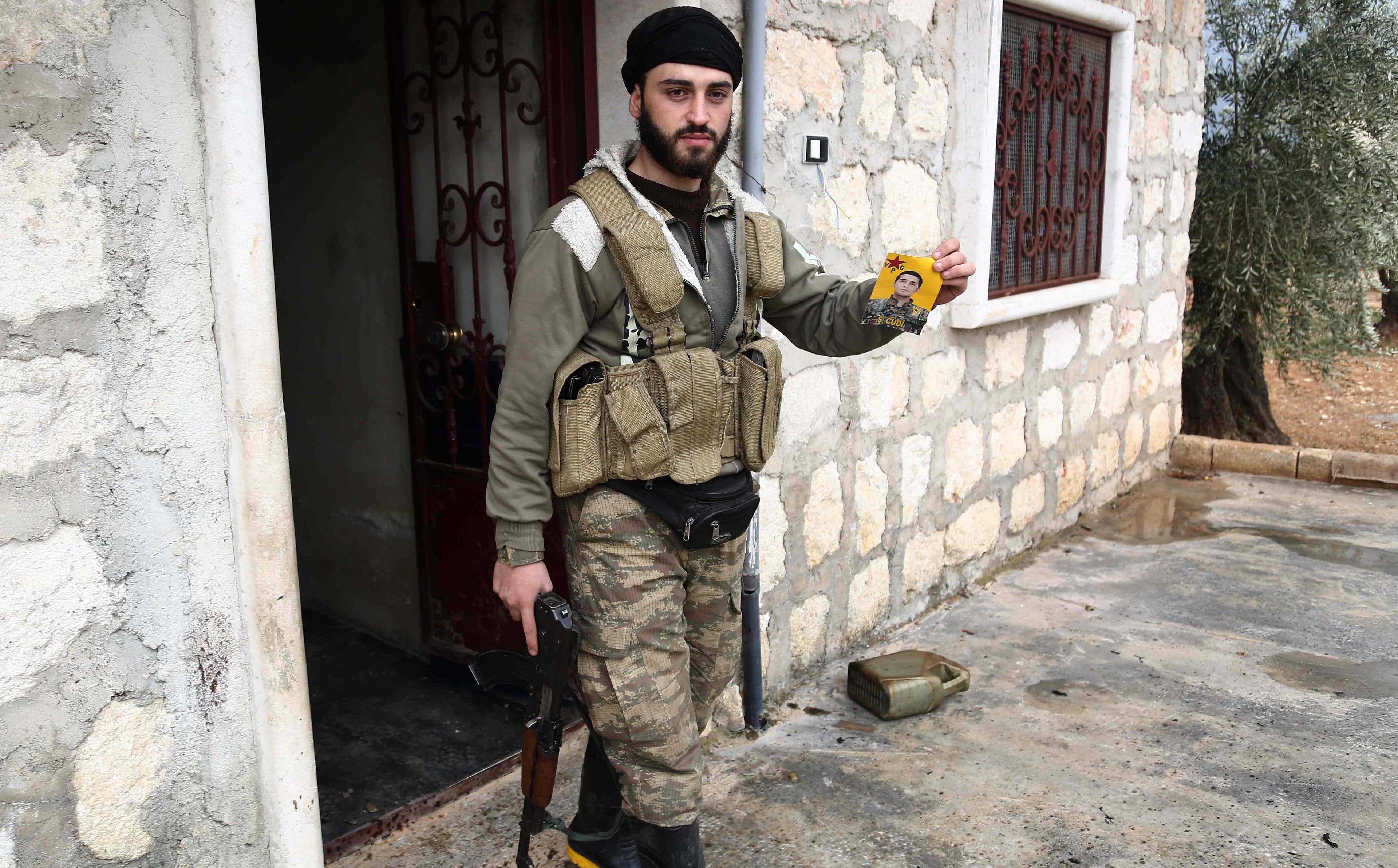 A Turkish-backed Syrian fighter holds a picture of YPG fighter in al-Bayyah village, northeast Afrin, on February 21. Photo: Nazeer al-Khatib/AFP