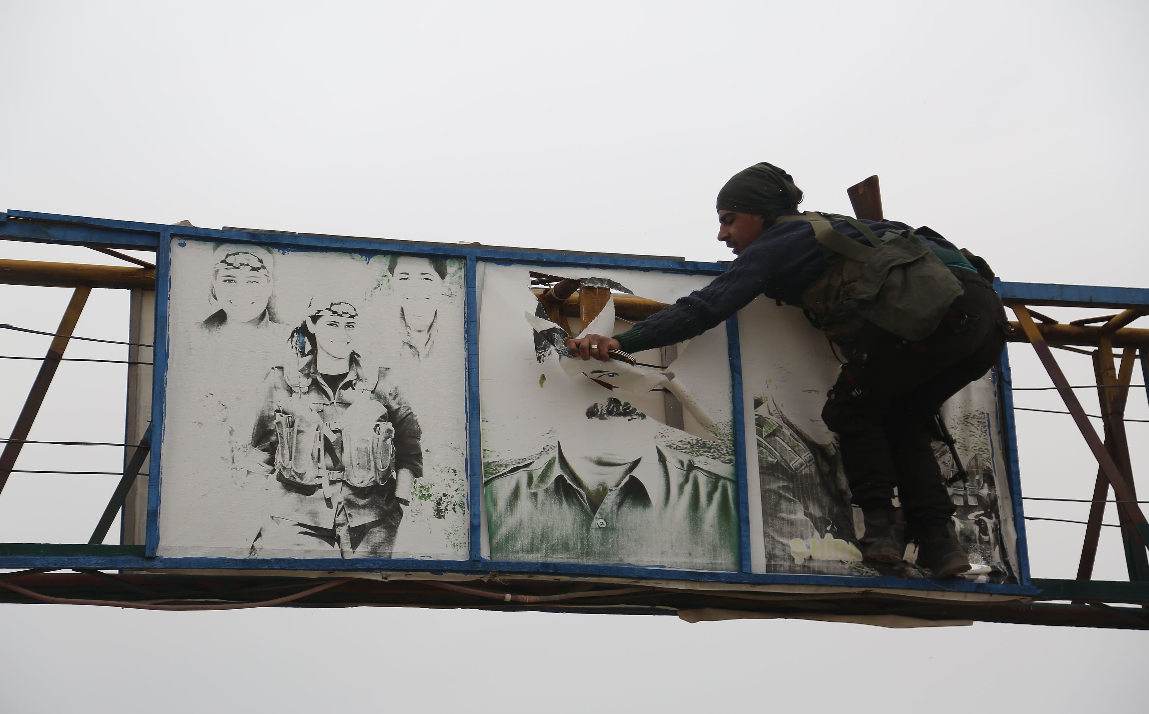A Turkish-backed Syrian fighter tears down a picture of Abdullah Ocalan north of Afrin during military operations in March. Photo: Nazeer al-Khatib/AFP