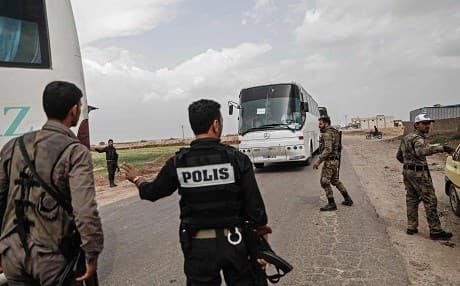Turkish-backed Syrian rebel police and special forces in Azaz direct buses carrying evacuees from Dumayr. Most of the convoy of 31 buses then headed to Afrin. Photo: Sameer al-Doumy/AFP