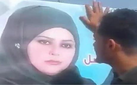 A man in Najaf kisses and touches his wet finger on the poster of a political candidate. Photo: Social media