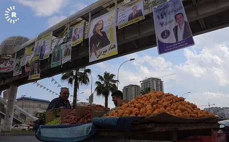 A vendor sells fruit below a crosswalk adorned with campaign posters in Erbil. Photo: Hejar Jawar/Rudaw