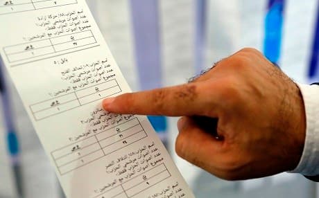 An electoral commission employee examines a printout from an electronic counting machine in Najaf on Sunday. Photo: Haidar Hamdani/AFP