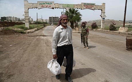 A man walks past armed guards at an entrance to Afrin city. Photo: Nazeer al-Khatib/AFP