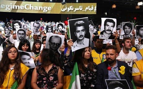 People hold up photos of family members killed by the Iranian regime during an MEK conference in Paris. Photo: Zakaria Abdelkafi/AFP