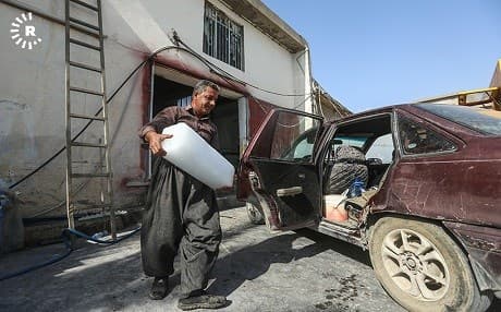 A man in Sulaimani, Kurdistan Region, carries a block of ice from a factory to his car on July 4, 2018. Photo: Sartep Othman | Rudaw