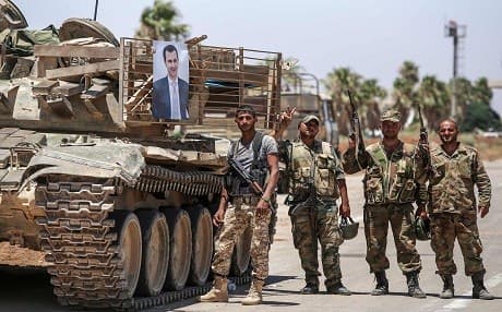 Syrian soldiers stand flashing the victory gesture next to a picture of Syrian President Bashar al-Assad hanging on a tank at the Nassib border crossing with Jordan in the southern province of Daraa on July 7, 2018. Photo: Youssef Karwashan | AFP