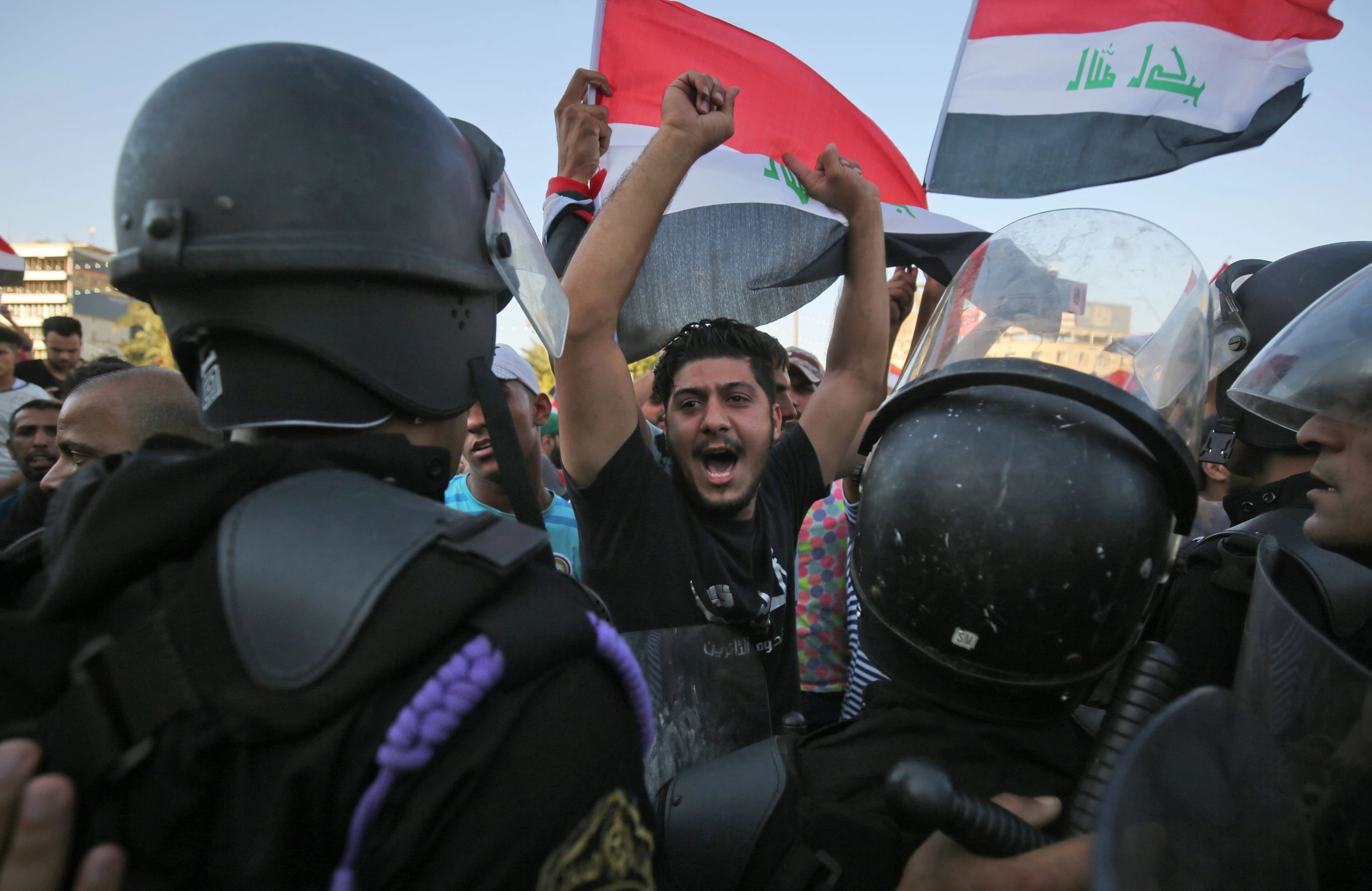Iraqi protesters shout slogans and wave national flags as they face security forces during clashes at a demonstration against unemployment and a lack of basic services in the capital Baghdad's Tahrir Square, July 20, 2018. Photo: Ahmad al-Rubaye / AFP