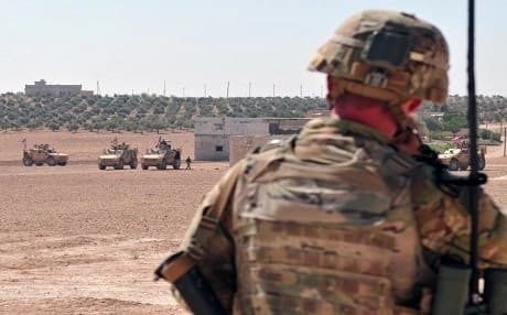 A US soldier checks radio communication with U.S. forces during an independent, coordinated patrol outside Manbij, Syria, July 28, 2018. Photo: Sgt. Nicole Paese | US Army