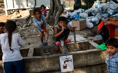 Refugees and migrants clean themselves and wash their clothes at a camp outside the Moria refugee camp in the island of Lesbos on August 5, 2018. Photo: Aris Messinis AFP