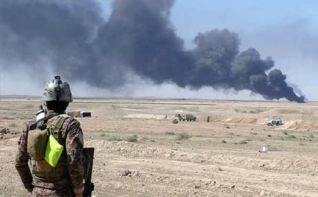 An Iraqi soldier looks at smoke billowing from Ajeel oil field in March 2015. File photo: AFP