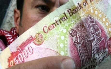 A man in the Kurdistan Region's capital of Erbil inspects a 25,000 Iraqi dinar banknote. Photo: Ali al-Saadi | AFP