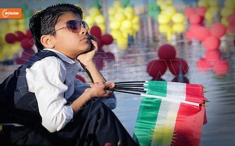 A boy holding Kurdish flags. Photo: Rudaw