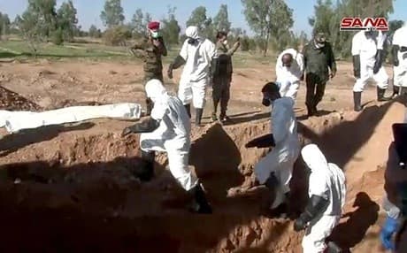 Syrian civil defense workers and members of the Syrian Arab Red Crescent exhume bodies from an ISIS mass grave near al-Boukamal. Photo: SANA
