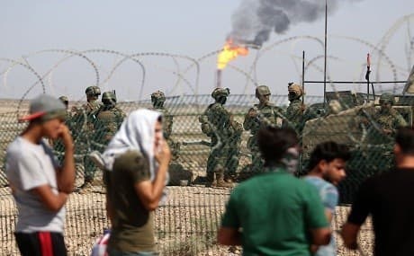Protesters demonstrate as Iraqi soldiers stand guard oil fields in al-Qurnah, some 100 kilometers north of Basra, southern Iraq, on July 14, 2018. Photo: Haidar Mohammed Ali / AFP