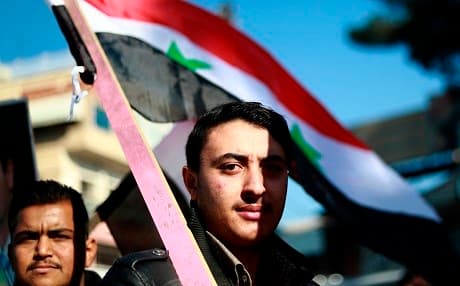 Demonstrators wave the Syrian national flag during a demonstration in the northeastern Syrian Kurdish-majority city of Qamishli on December 23, 2018, asking for the Syrian army's protection as Turkey threatens to attack. Photo: Delil Souleiman/AFP