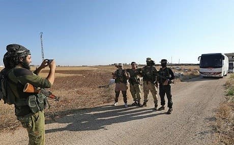 Members of Hayat Tahrir al-Sham pose for a photo in front of a convoy of buses getting ready to evacuate the Syrian towns of Fuaa and Kefraya in July 2018. File photo: Omar Haj Kadour/AFP