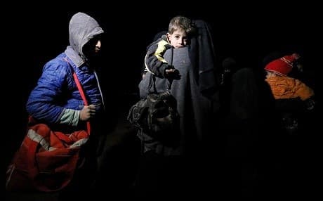 A woman carries a child as she walks with other children in the dark near the Omar oil field in the Deir ez-Zor countryside on January 25, 2019. They are one of a group of families fleeing ISIS-held territory. Photo: Delil Souleiman/AFP