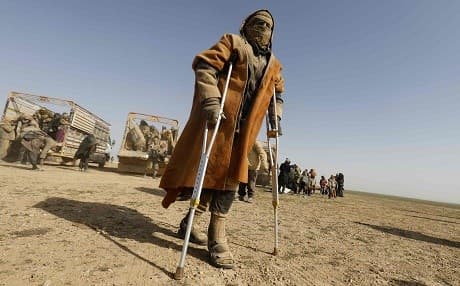 A man uses crutches to walk as people who fled battles between Syrian Democratic Forces (SDF) and fighters from ISIS in Baghouz arrive after crossing a desert in the back of a truck to a region controlled by the SDF on January 26, 2019. Photo: Delil Souleiman/AFP