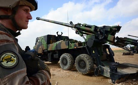 A French member of the coalition against ISIS stands guard in front of a wheeled 155 mm gun-howitzer CAESAR system near al-Qaim, Iraq on Saturday, a few kilometres from Baghouz. Photo: Daphné Benoit/AFP