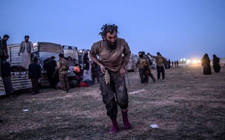 A man suspected of belonging to the Islamic State (ISIS) walks past members of the Kurdish-led SDF after leaving al-Baghouz, Syria province on March 4, 2019. Photo: Bulent Kilic | AFP 