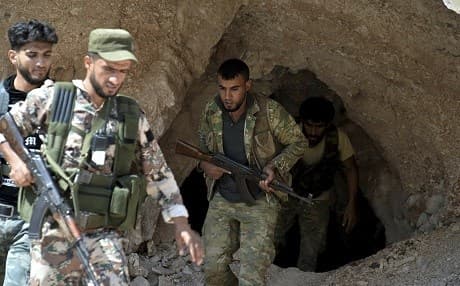 In this September 9, 2018 photo, fighters with the Free Syrian Army exit a cave where they live, on the outskirts of the northern town of Jisr al-Shughur, west of Idlib, Syria. File photo: Ugur Can/DHA via AP