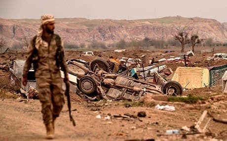 An SDF fighter walks past damaged vehicles on the side of a road in the village of Baghouz, eastern Syria, March 24, 2019. Photo: Delil Souleiman / AFP