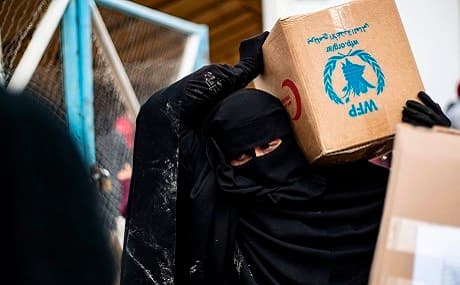 A veiled woman in Al-Hol camp carries an aid box of food supplies, March 28, 2019. Photo: Delil Souleiman / AFP 