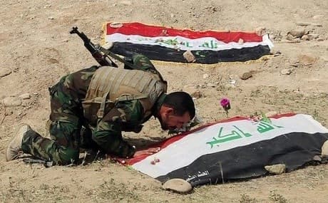 A Shiite militiaman kisses a grave in Speicher, Tikrit. File photo: AP 
