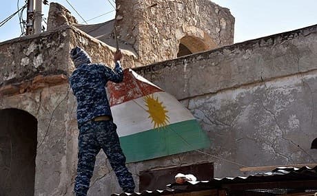An Iraqi soldier removes a Kurdish flag from Altun Kupri, 25 miles north of Kirkuk city. File photo: Emad Matti / AP 