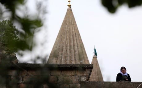 A Yezidi woman stands solemnly in front of the holy Lalish Temple in the Kurdistan Region of Iraq in 2015. File photo: Safin Hamed | AFP