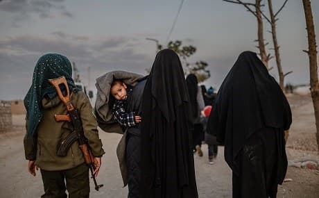 Veiled women, reportedly wives of Islamic State fighters, walk with their children under the supervision of a female fighter from the Syrian Democratic Forces (SDF) at al-Hol camp in Hasaka, northeastern Syria, February 17, 2019. Photo: Bulent Kilic / AFP