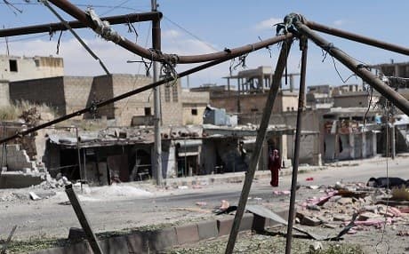 A woman walks along buildings damaged during reported shelling by government forces on the town of Khan Sheikhun in the southern countryside of the rebel-held Idlib province. Photo: Omar Haj Kadour/AFP
