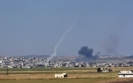 Smoke from an incoming shell billows above Kafr Nabuda as a rocket fired from the town leaves a white trace of smoke, in Hama governorate, Syria, during reported air strikes by Syrian regime forces on May 26, 2018. Photo: George Ourfalian | AFP
