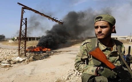 A fighter with the Turkish-backed National Liberation Front (NLF) holds a position in Syria's Hama province on June 6, 2019. Tires in the background are set ablase to create a smoke screen against air strikes by regime forces. Photo: Omar Haj Kadour | AFP