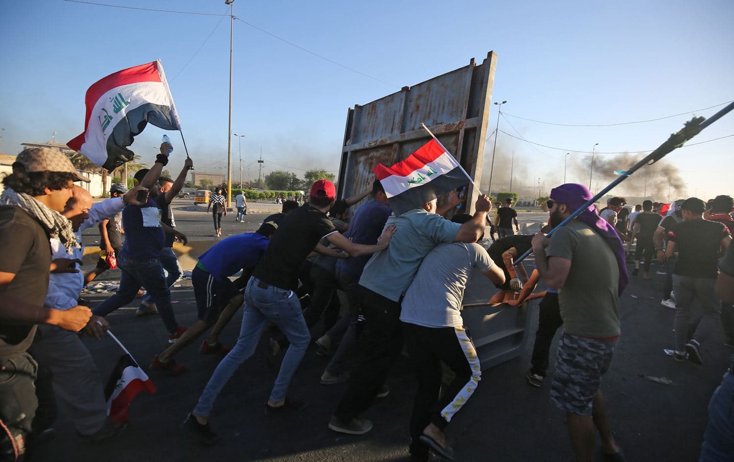 Iraqi protesters take cover during a demonstration against state corruption, failing public services, and unemployment, in the Iraqi capital Baghdad's central Khellani Square on October 4, 2019. Photo: Ahmad al-Rubaye/AFP